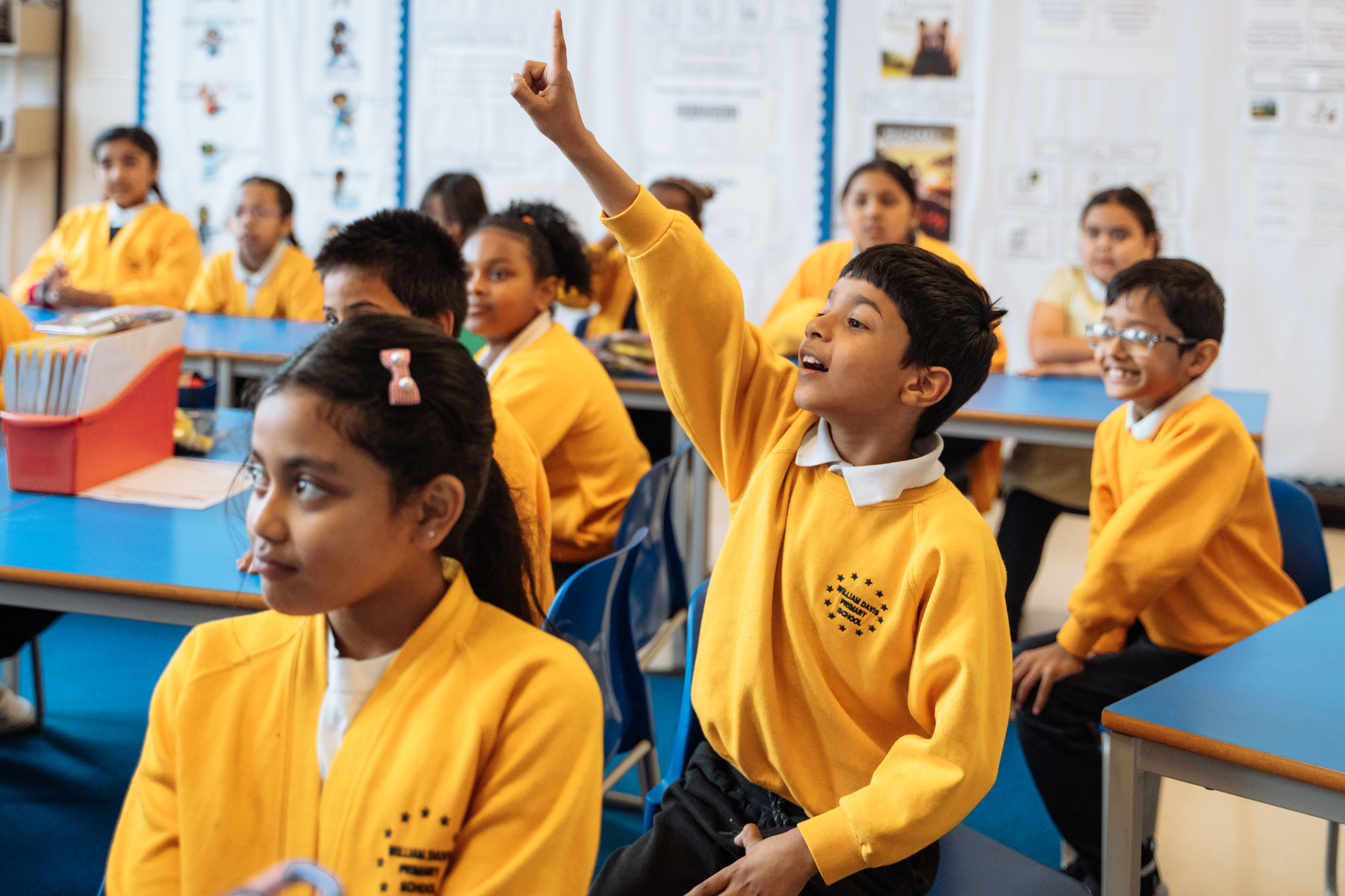 Children raising hands in class