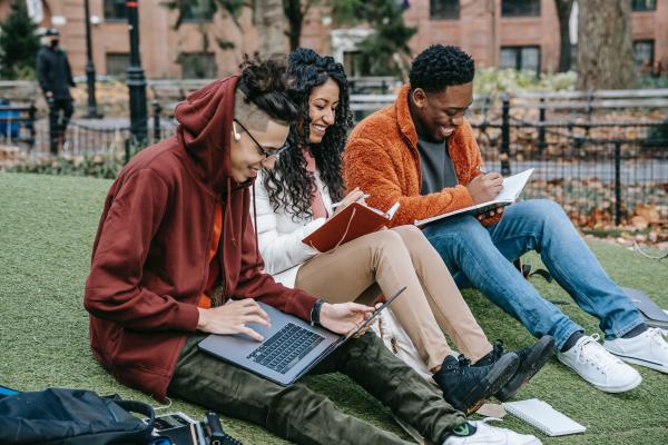 A group of people with laptops and notebooks, learning together